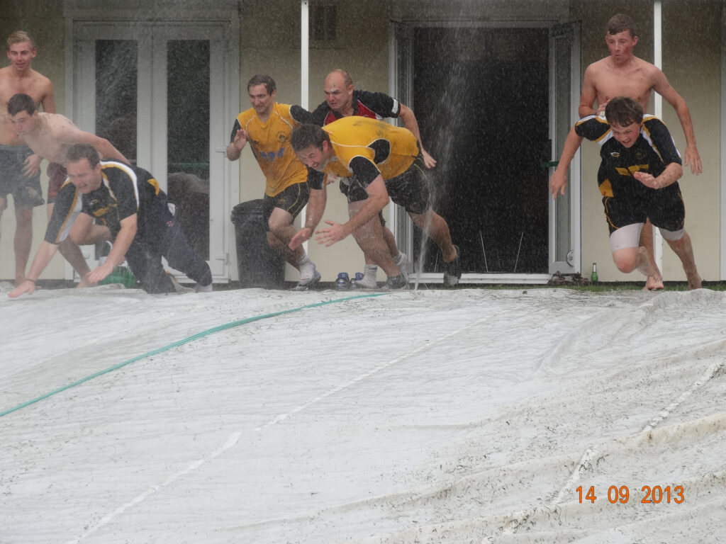 men racing down the hill on the wet tarpaulin