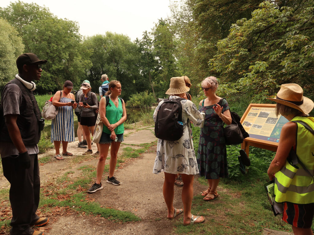 walkers chatting at old river swimming baths with display panel