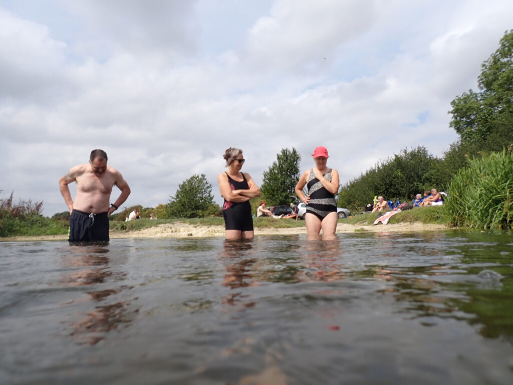swimmers in the river Little Ouse with picnickers in the background