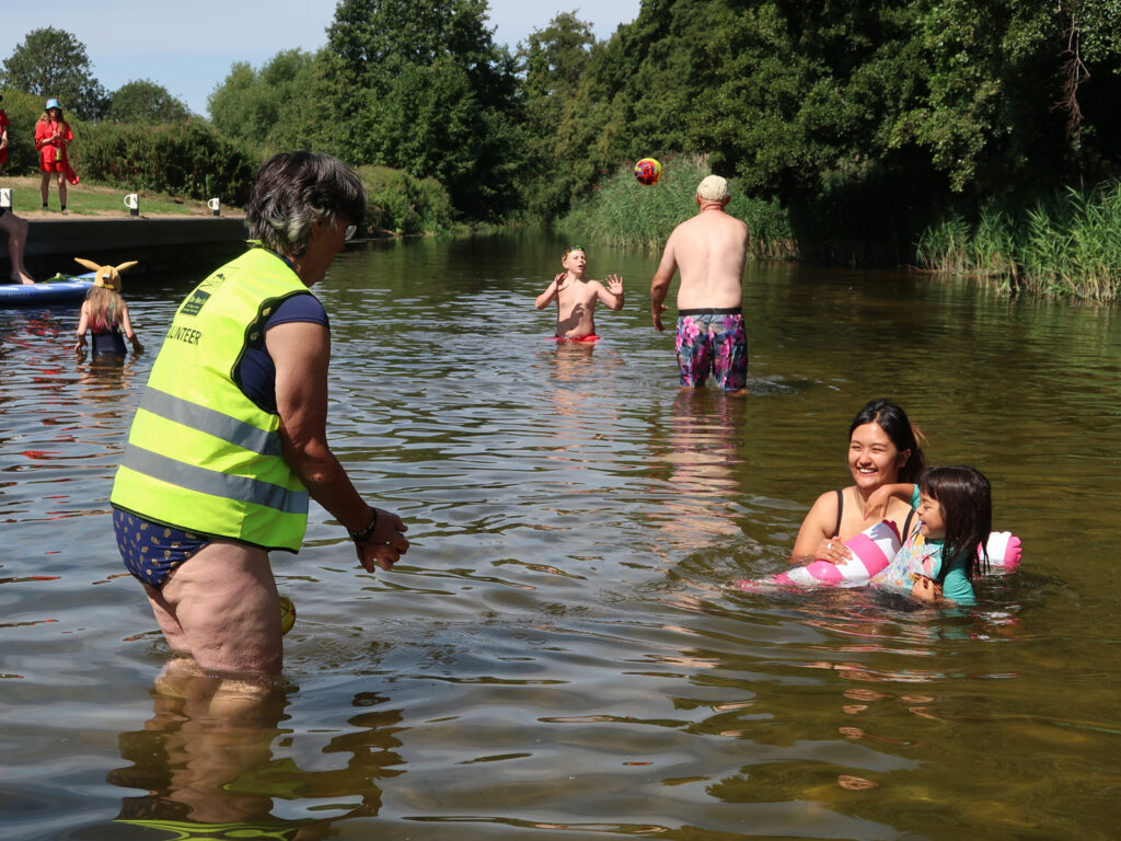 families and children playing in the water with volunteer and lifeguard at intro session Brandon Staunch