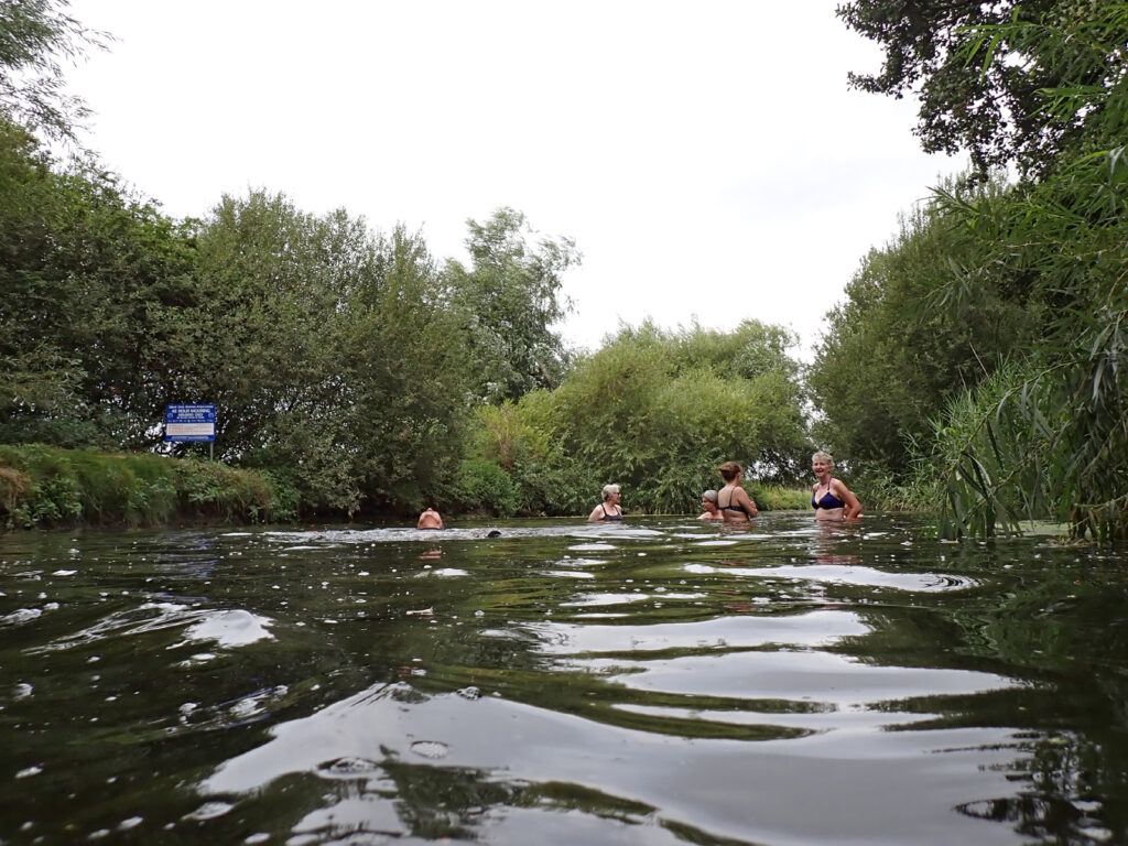 swimmers in river with trees and foliage and GOBA mooring sign